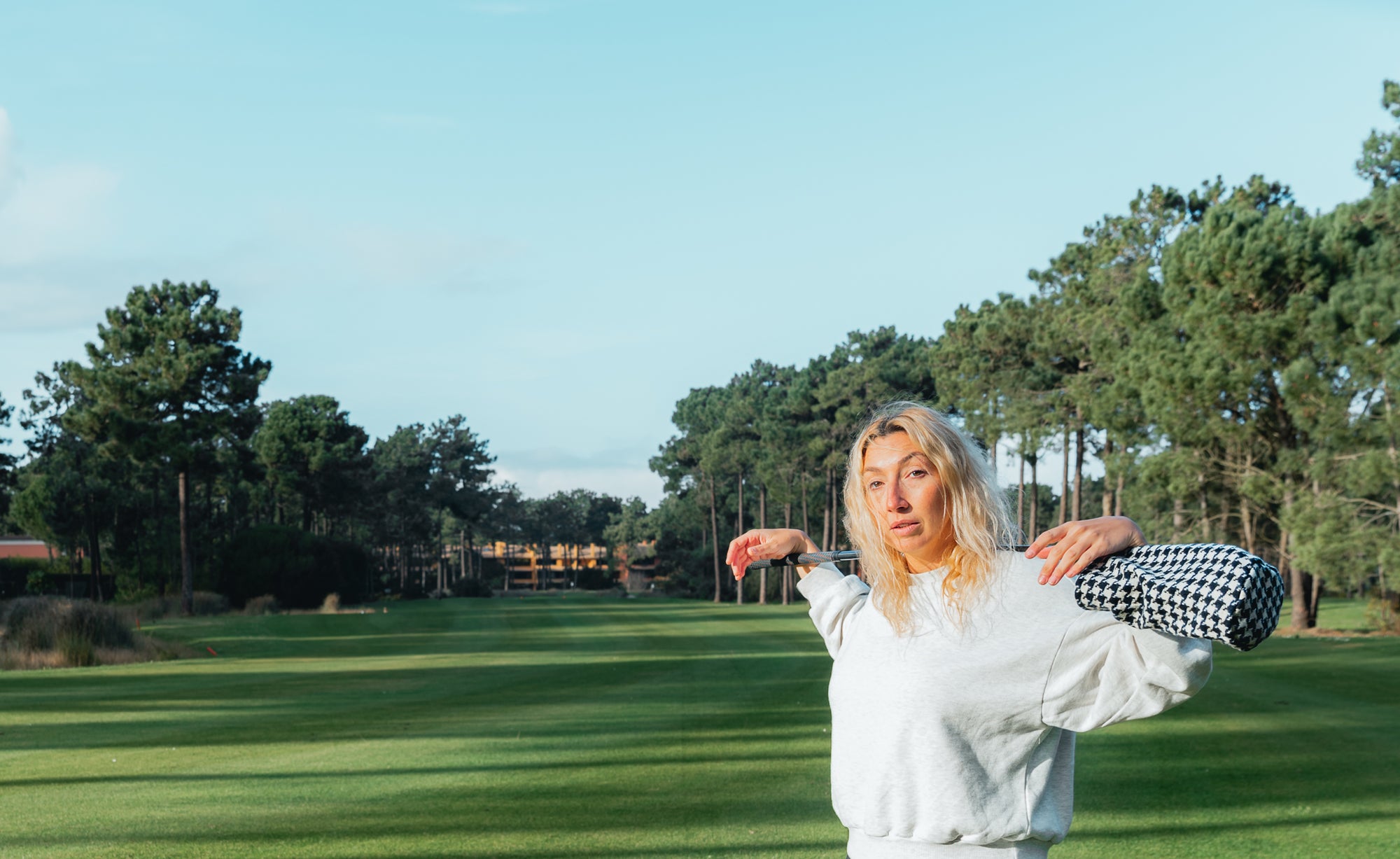 Female golfer holding a golf club and headcover at Aroeira golf course in Portugal